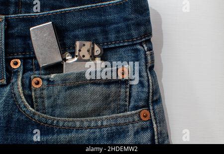Metal lighter close up in denim pocket on white background Stock Photo