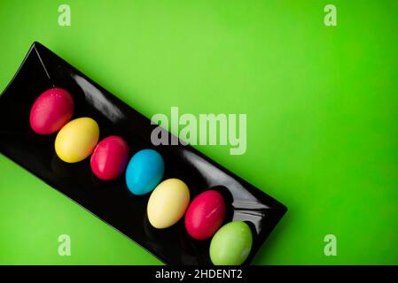 Easter eggs on a rectangular black ceramic dish. Green background. Copy space for text. Stock Photo