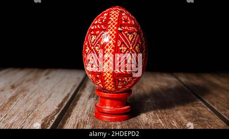 Closeup of a hand-painted red egg on a wooden table, traditional in Romania for Easter Stock Photo