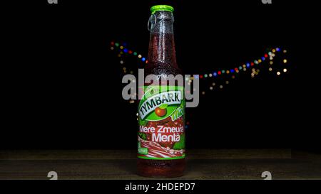 A closeup of a Tymbark glass bottle with raspberry and mint flavor, isolated on black background with colored lights Stock Photo
