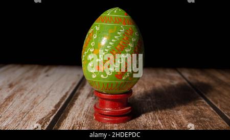 Closeup of a hand-painted green egg on a wooden table, traditional in Romania for Easter Stock Photo