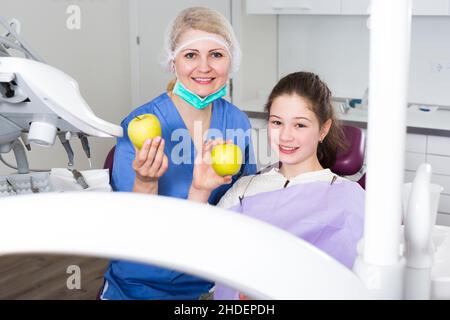Happy girl with female dentist showing apples Stock Photo