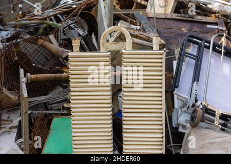 Multi colored cast iron radiators, old heating elements stacked in heap. Old batteries made of cast iron lying on the ground Stock Photo