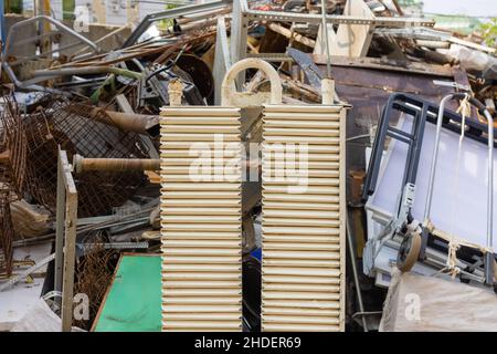 Multi colored cast iron radiators, old heating elements stacked in heap. Old batteries made of cast iron lying on the ground Stock Photo