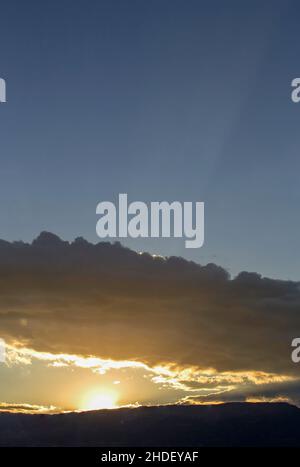 The sun between the mountain and a dense cloud at sunset, near he colonial town of Villa de Leyva, in central Colombia. Stock Photo