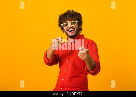 Hey you. Portrait of cheerful bearded man pointing to camera, smiling, making happy choice, we need you concept. Indoor studio shot isolated on orange background Stock Photo