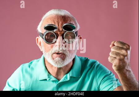 Portrait of humoristic senior man with flying goggles feeling angry and looking at camera. Stock Photo