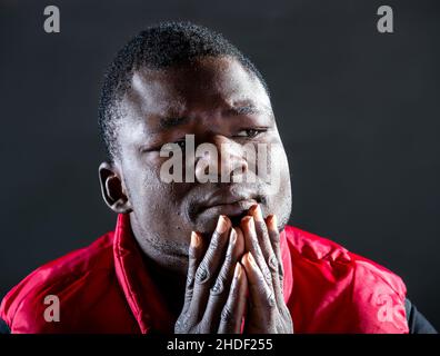 Young black man thinking of something against black background Stock Photo