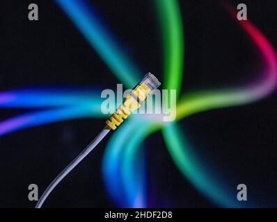 Internet cable and yellow ethernet connector in close up against a colourful background. Stock Photo