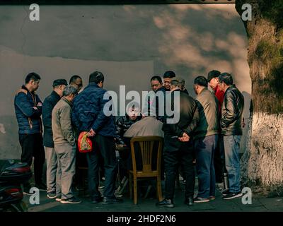 Group of males standing around a table and talking in Hangzhou, China Stock Photo