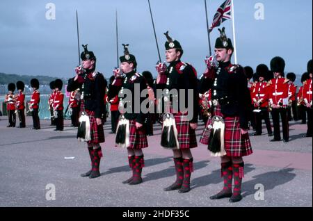 Four members of the Scots Guard wearing dance slippers instead of combat boots during a special performance band in the background in military uniform Stock Photo
