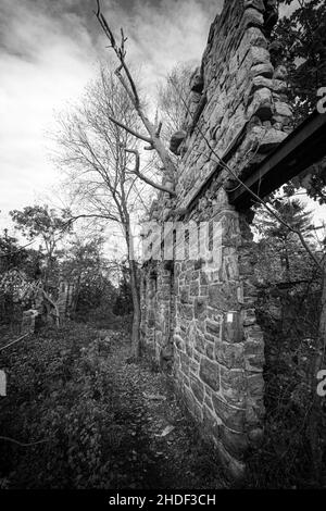 Vertical shot of an abandoned old ruin stone building under a cloudy sky in grayscale Stock Photo