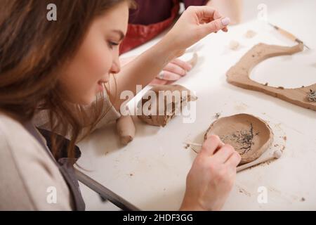 Close up of a woman making ceramic plate at clay workshop Stock Photo