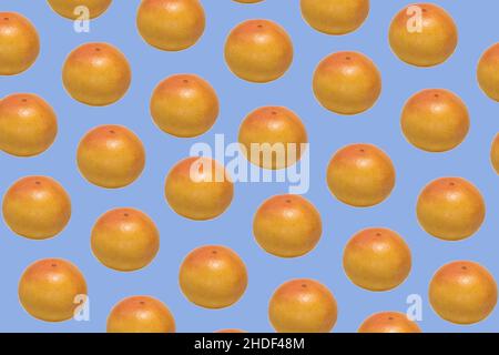 Pattern made of whole ripe ruby grapefruit on blue background Stock Photo