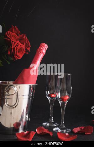 Romantic dating with champagne, red roses on black background. Valentine's day. Vertical format. Stock Photo