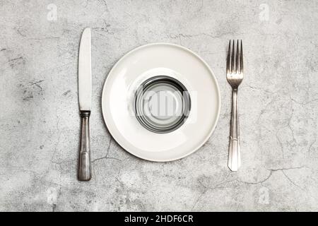 Can of preserves on a plate with cutlery and on a marble background in a top view Stock Photo