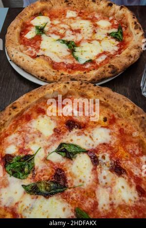 Two freshly baked napolitano pizzas on a table Stock Photo