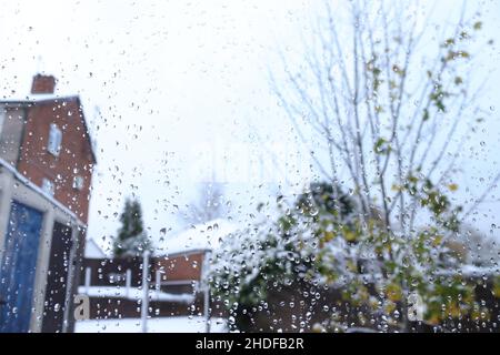 Rain and melting snow on window with back yard in background Stock Photo