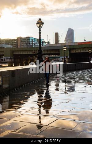 Man walking along the river Thames, Cannon Street railway bridge behind,  London Stock Photo