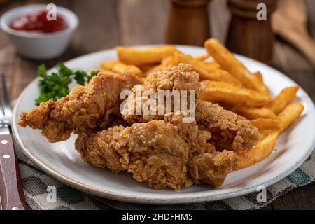 Crispy fried chicken tenders and french fries garnished with parsley on a plate Stock Photo