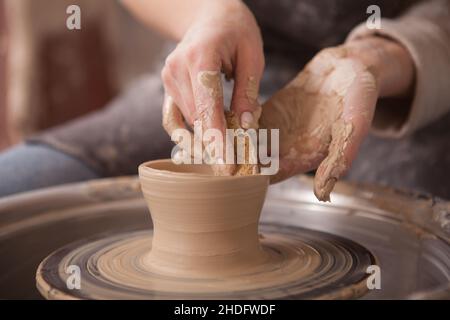 Unrecognizable woman making pottery, using potters wheel to shap clay mug Stock Photo