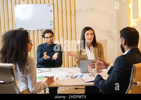 Successful young multiracial team in modern office. Group of young smart people discussing development strategy of company while sitting at the table Stock Photo