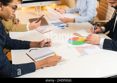 Multiracial team working in the office. Young team of sales managers are working in the office, making notes and discussing something. Serious atmosphere Stock Photo
