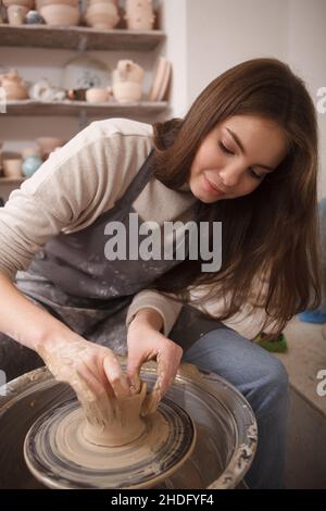 Beautiful woung woman making clay mug, using potters wheel Stock Photo