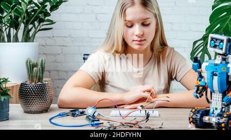A blonde teen girl plugging cables to sensor chips while learning ...