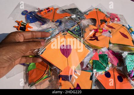 Female hand holding Kite and buying small kites during Indian kite festival Makarsankranti or Uttarayan. Many kites in packets sold in India Stock Photo