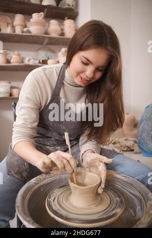 Vertical portrait of a lovely female artist making pottery on potters wheel Stock Photo
