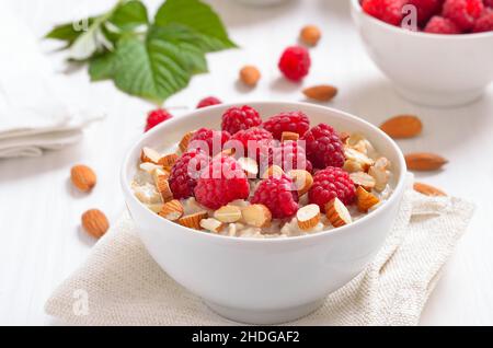 Oatmeal porridge with raspberries and nuts in bowl Stock Photo