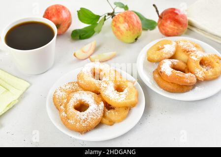 Apple rings on white plate, cup of black coffee on light stone background Stock Photo