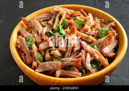 Slow cooked pulled pork for sandwiches with parsley in wooden bowl, close up view Stock Photo