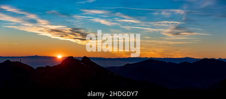 dramatic beautiful sunset seen from mountains in Italy with clouds illuminated by last orange sunbeams, panorama Stock Photo
