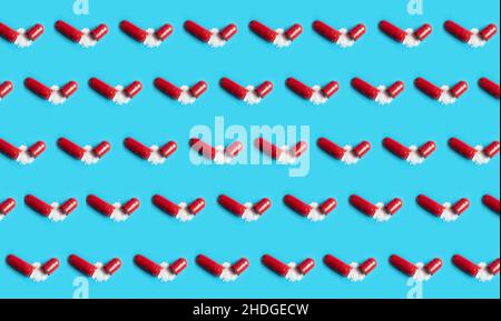 Lot of opened red gel capsules with white powder on blue background. Medical background concept. Stock Photo