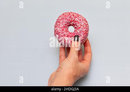 female hand holding donut on yellow green background Stock Photo