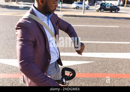 African american businessman with bicycle using smartwatch on the street on the go to office Stock Photo