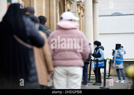 Members of the staff check people queuing outside a vaccination centre on Christmas Day in London as the Omicron variant reportedly spreads. Stock Photo