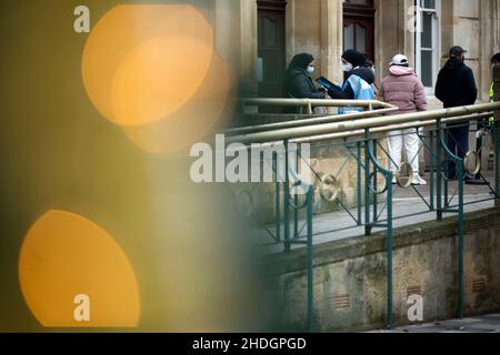 Members of the staff check people queuing outside a vaccination centre behind Christmas decorations on Christmas Day in London. Stock Photo