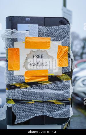 Free Parking sign stuck on a broken parking ticket machine (covered up) in UK public car park. Stock Photo