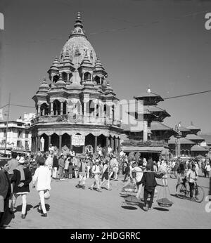 1950s, historical photo by J Allan Cash of a street scene in Kathmandu, Nepal, It shows activity in Durbar Square, home to many of the city's historic buildings and religious monuments, including its famous Hindu temples, where many take pilgrimage to. Stock Photo