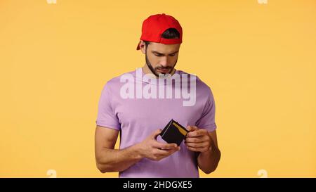 upset man holding empty wallet isolated on yellow Stock Photo