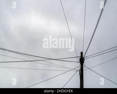 Telegraph pole with many cables, urban street. Stock Photo