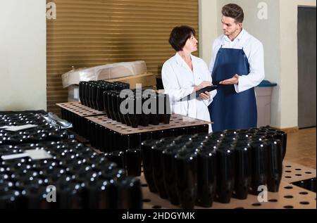 Two workers controlling number of wine bottles at sparkling wine factory Stock Photo
