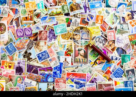 Stamp pliers and a magnifier on top of a stack of stamps from all around the world. Stock Photo