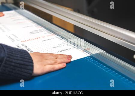 Worker with paper cutter machine in print house. Printing industry background Stock Photo