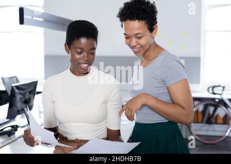 Multiracial businesswomen discussing over documents in creative office Stock Photo