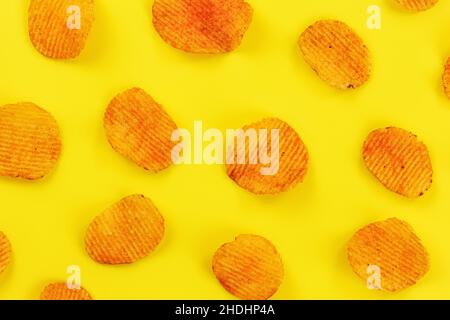 Potato crisps orange from paprika flavouring arranged on yellow board, view from above Stock Photo