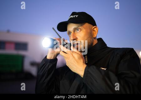 Security Guard Officer Using Walkie-Talkie Radio At Night Stock Photo